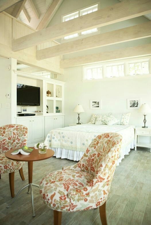 Bright bedroom before its Feather My Nest redesign, with floral chairs, pale bedding, and white built-in cabinetry